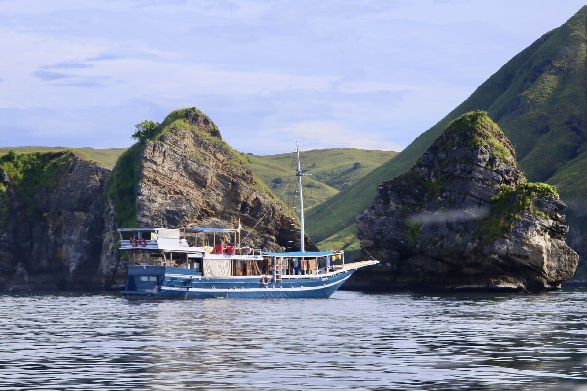 reiseblog-indonesien-flores-komodo-inseln-urlaub-sonne-palmen-strand-boot-vor-felsen-reise